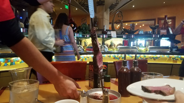 meat skewers being served at tucanos brazilian grill